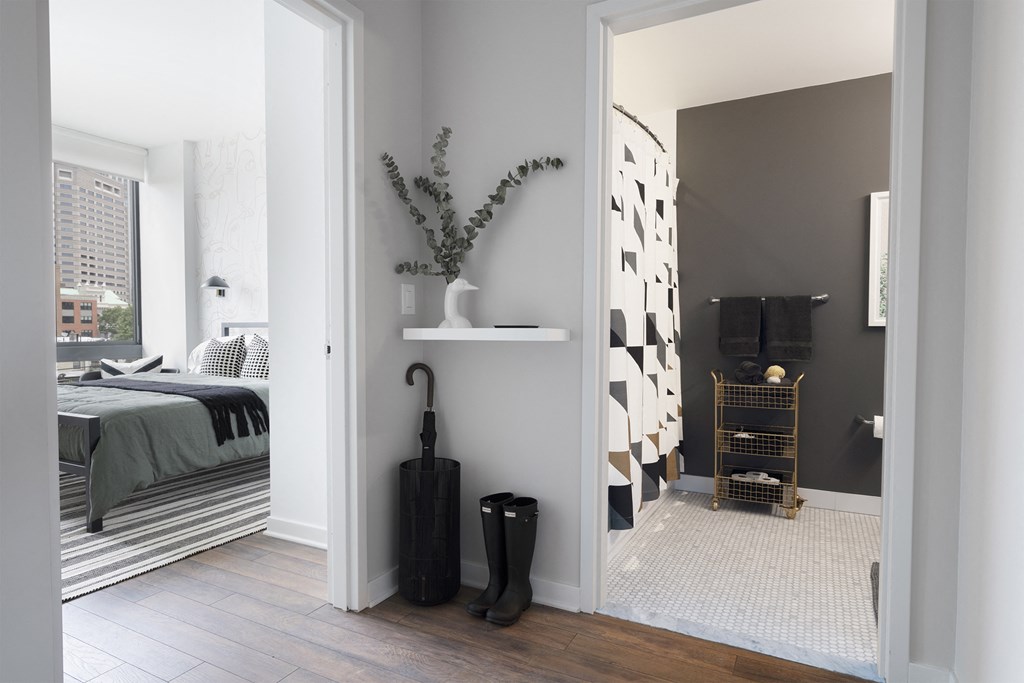 a bedroom with a bed and a hallway with a black umbrella and a vase