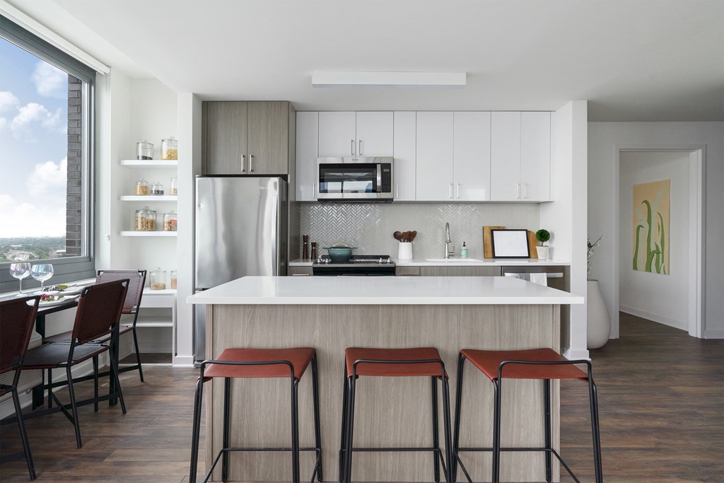 a kitchen with white cabinets and a counter with three stools