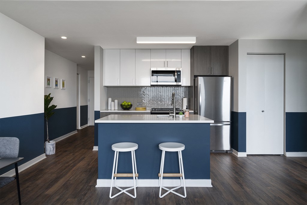 a kitchen with white cabinets and a blue island with three stools