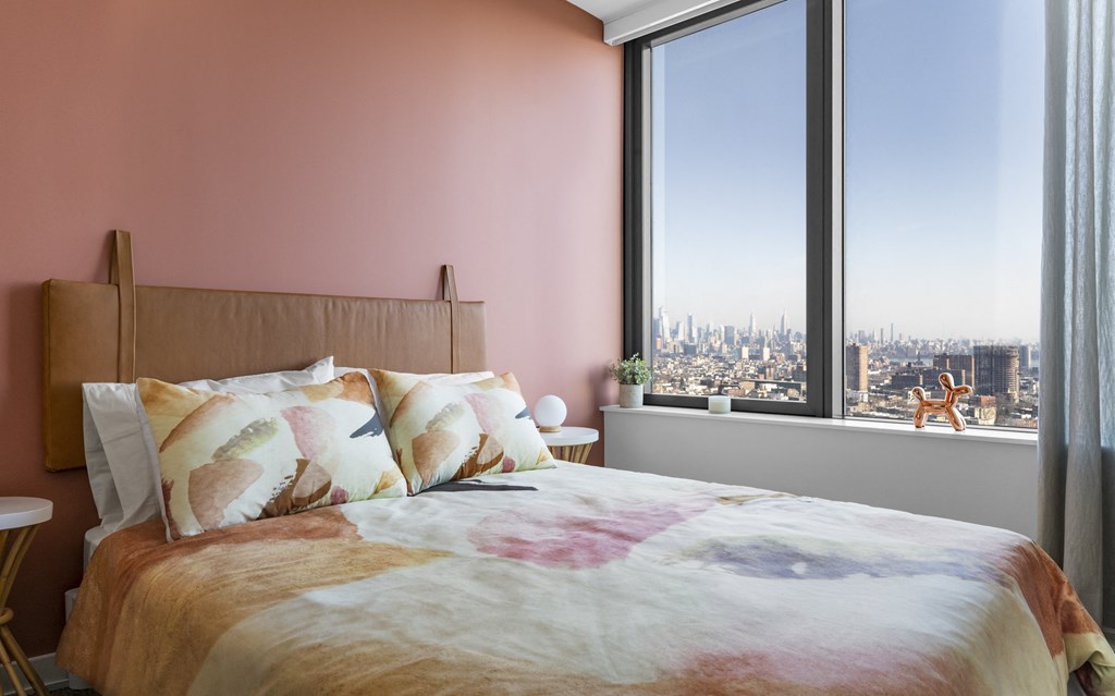 a bedroom with pink walls and a bed with pillows and a window