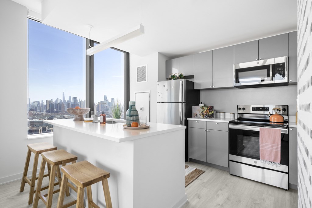 a white kitchen with a large window and a white island with three stools
