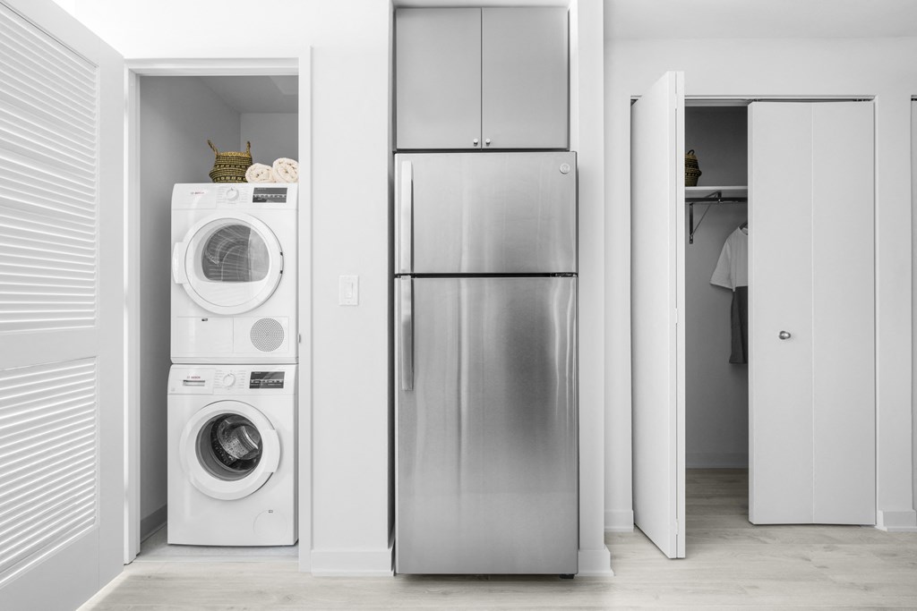 a white laundry room with a washer and dryer and a stainless steel refrigerator