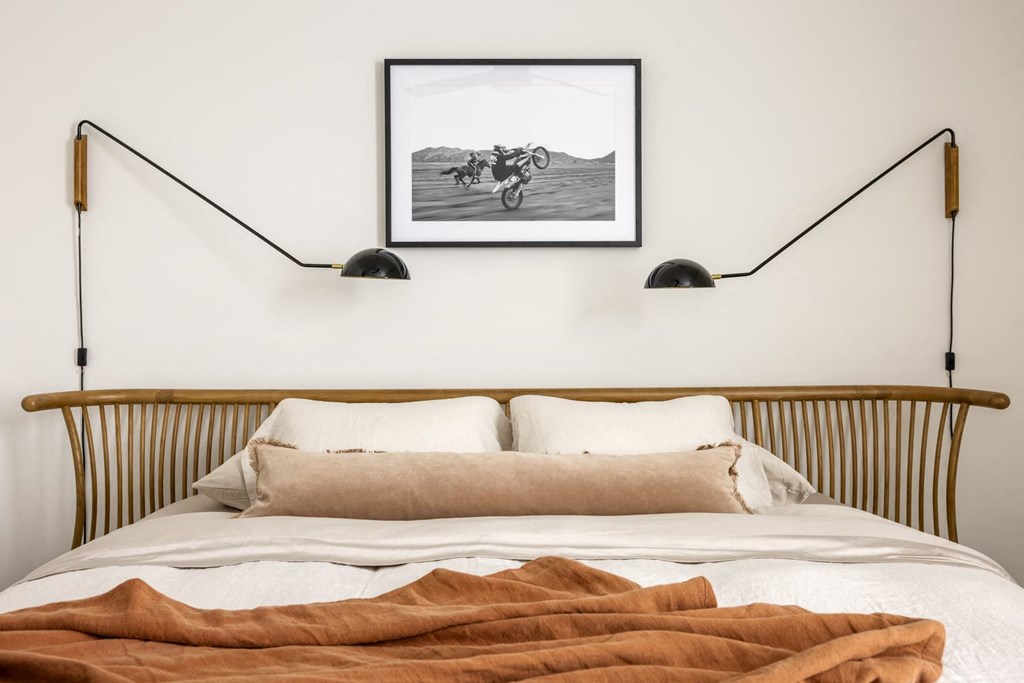 a bedroom with a bed and two lamps over it