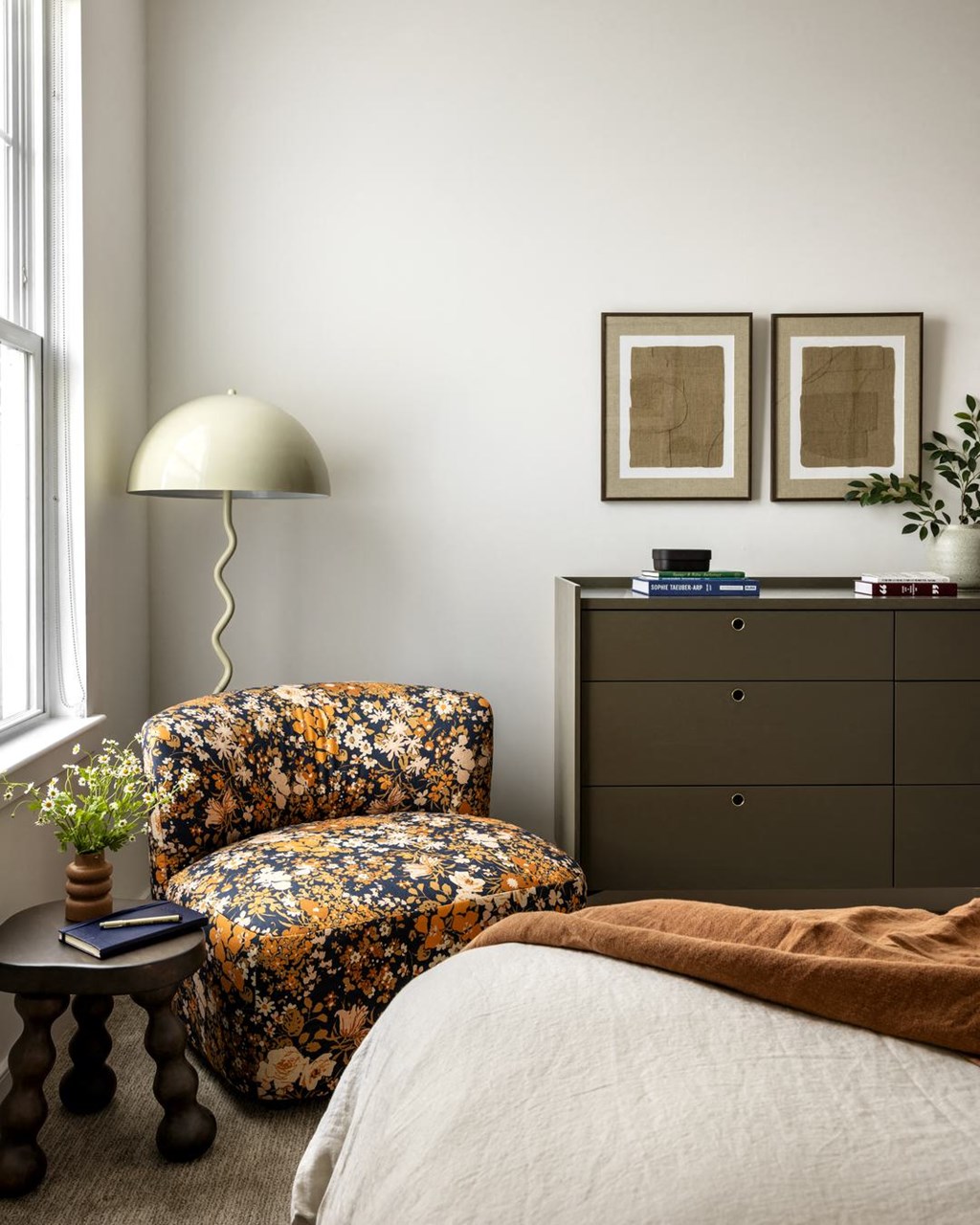 a bedroom with a chair and a lamp and a dresser