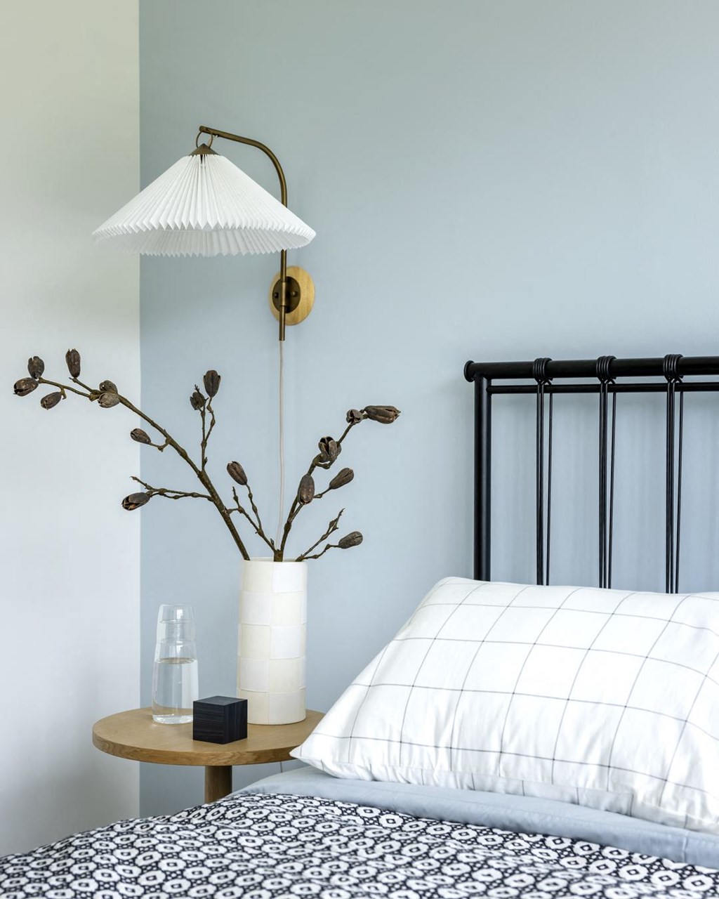 a bedroom with a bed and a lamp and a vase with flowers