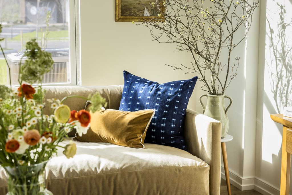 a living room with a couch and pillows and flowers