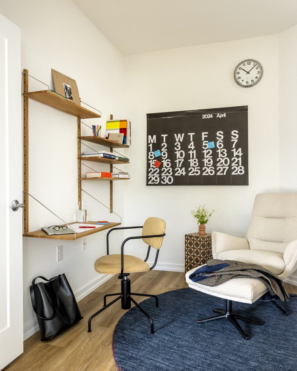 a living room with a chair and a desk and a calendar on the wall