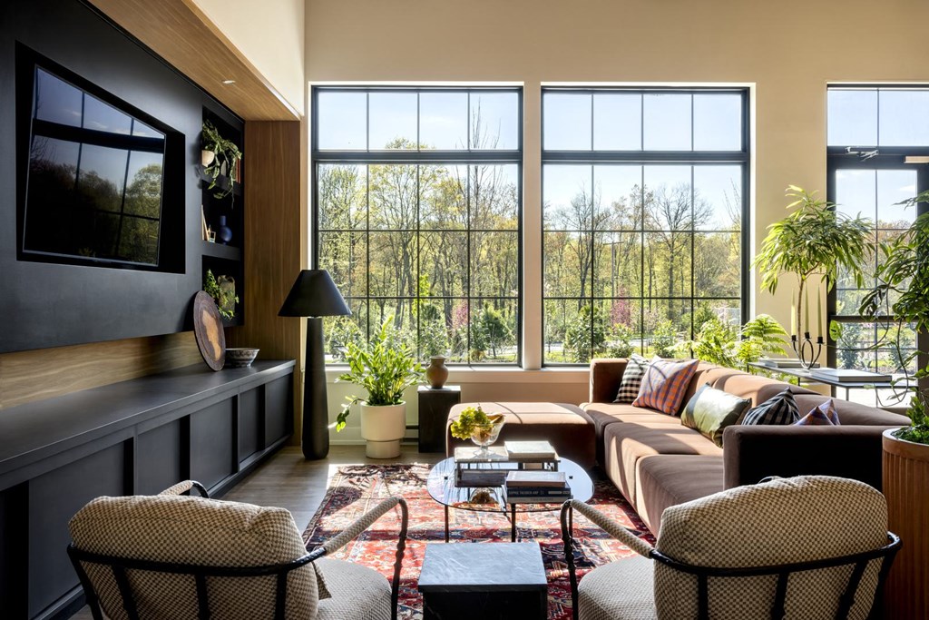 a living room with a couch and chairs and large windows