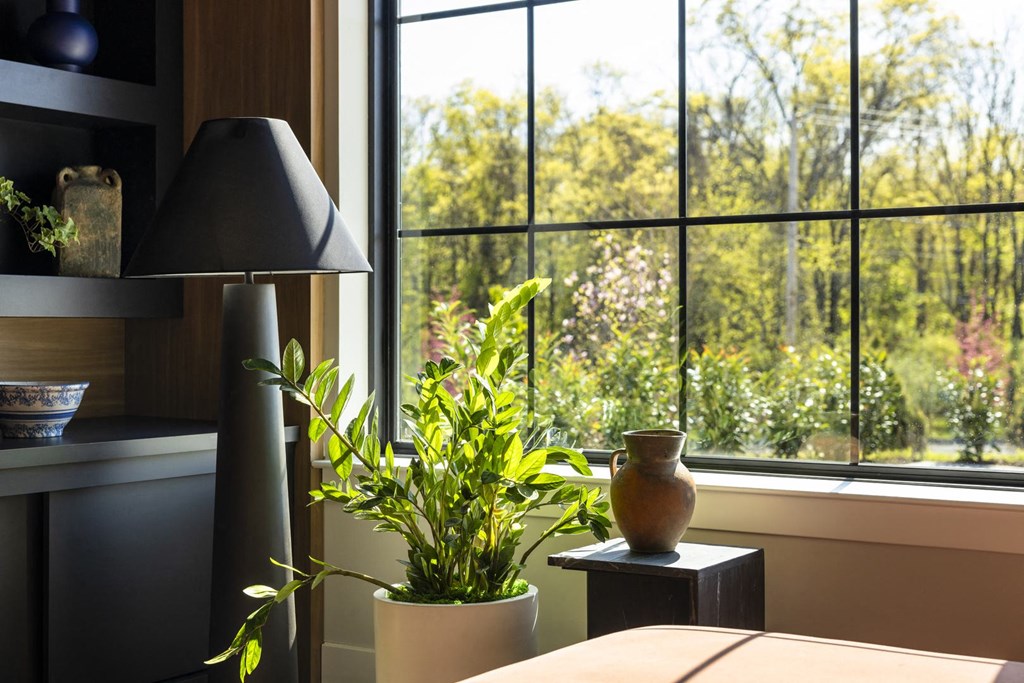 a table with a lamp and a plant in front of a window