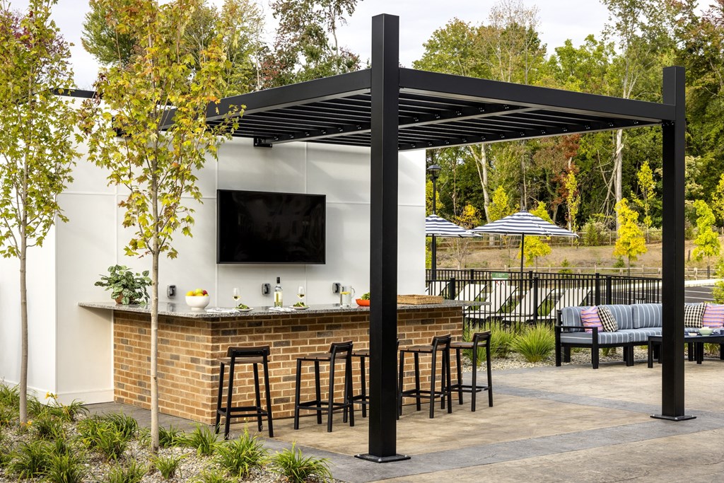 A small outdoor bar with a black canopy and a television mounted above it.