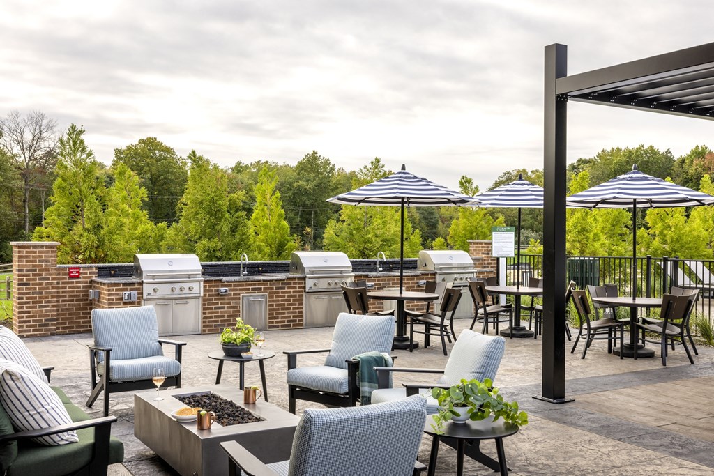 A patio with chairs and umbrellas overlooking a forest.