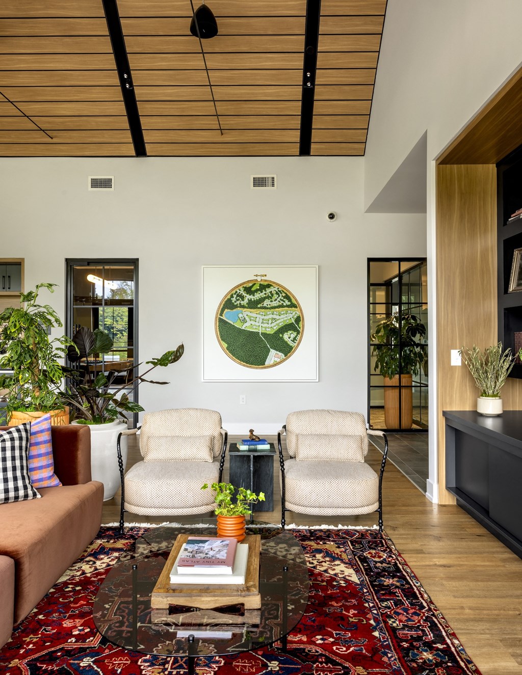 A living room with a rug, two chairs, a couch, and a painting on the wall.