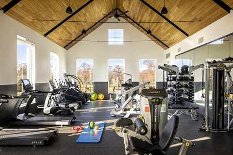 A gym with a variety of exercise equipment including treadmills, stationary bikes, and weight machines.