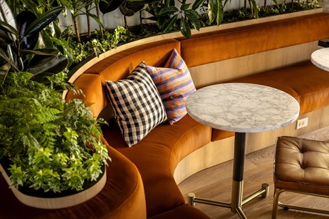 A round table with a white marble top is in the middle of an orange couch.