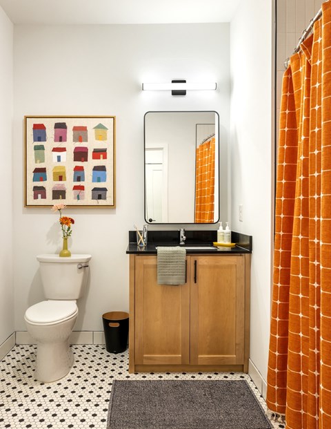 A bathroom with a toilet, sink, and orange shower curtain.