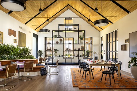A modern dining room with a wooden ceiling and a large table surrounded by chairs.