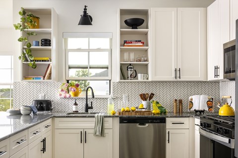 A kitchen with white cabinets and a black faucet.