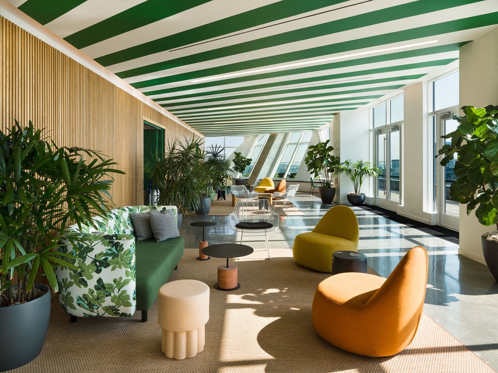 a lobby with plants and furniture in a building with large windows