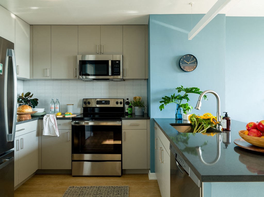 a kitchen with stainless steel appliances and a clock on the wall