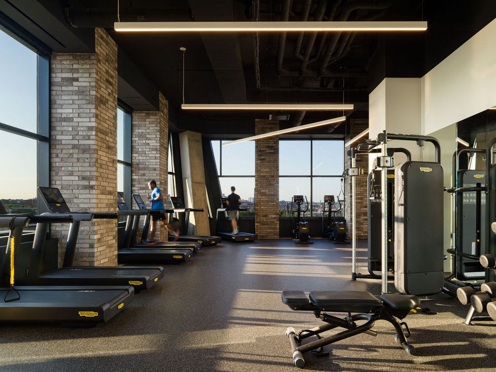 a gym with treadmills and weights on the floor and windows