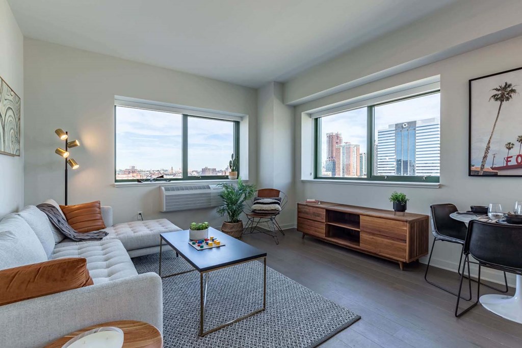 a living room with a couch and a table and three windows