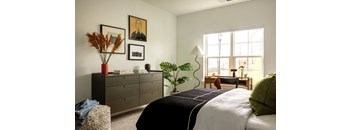 A bedroom with a large bed, a dresser, and a window.