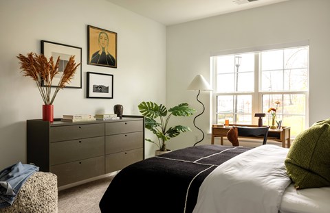 A bedroom with a large bed, a dresser, and a window.