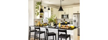A kitchen with black chairs and a black countertop.