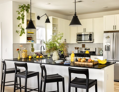 A kitchen with black chairs and a black countertop.
