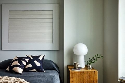 a bedroom with a bed and a lamp and a painting on the wall