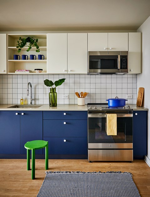 a kitchen with blue and white cabinets and a green stool