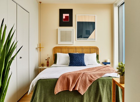 a bedroom with a bed with a wicker headboard and a green blanket