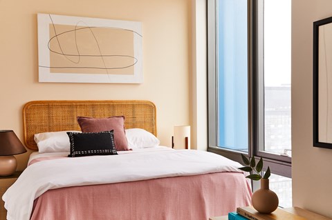 a bedroom with a bed with a pink comforter and pink pillows