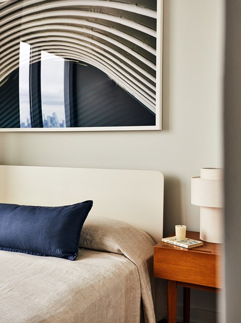 a bedroom with a bed with a blue pillow and a picture on the wall above