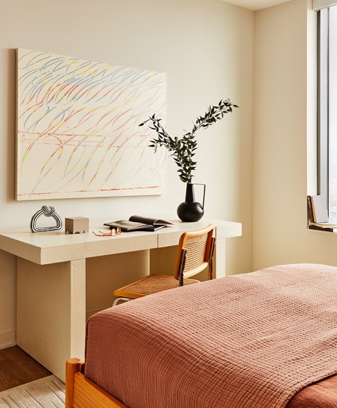 a bedroom with a bed and a desk with a vase and a painting
