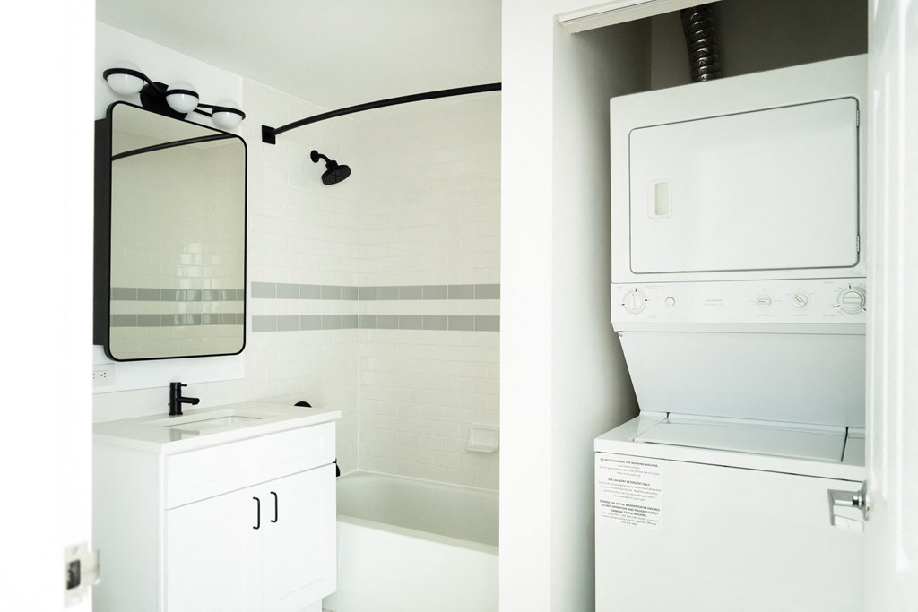 a white washer and dryer and a mirror in a bathroom