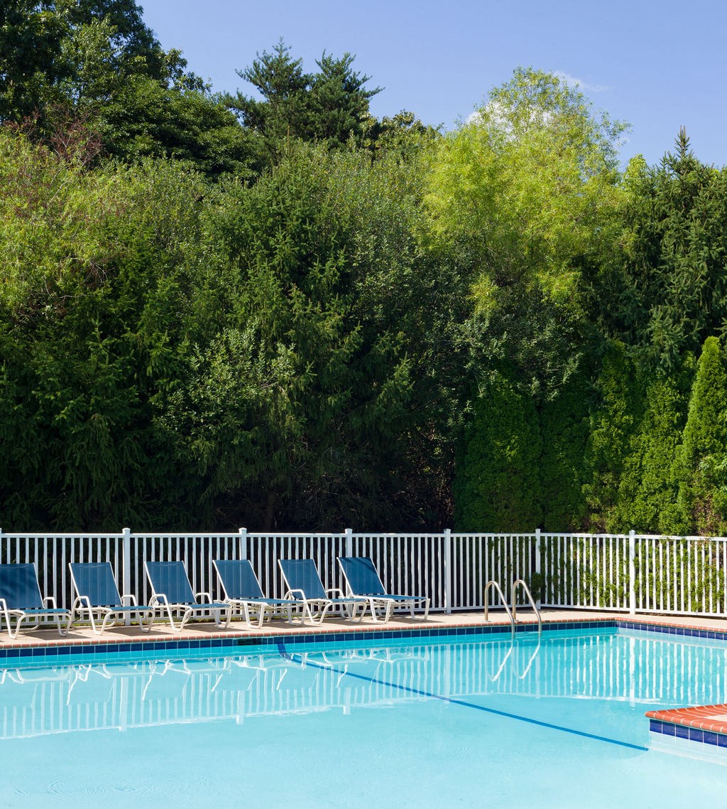 a swimming pool with blue chairs next to a white fence