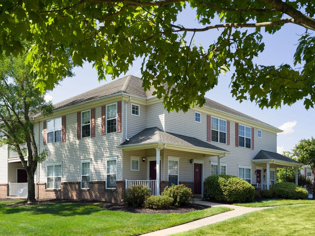 the front of a house with a lawn and a tree