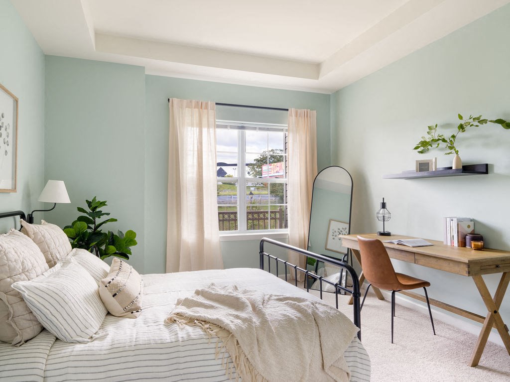 a bedroom with blue walls and a bed and a desk with a mirror