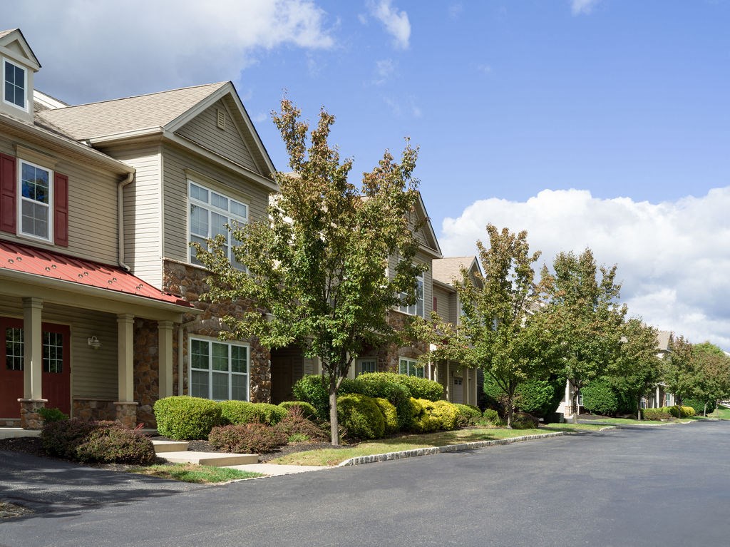 a row of houses with trees and bushes in front of them