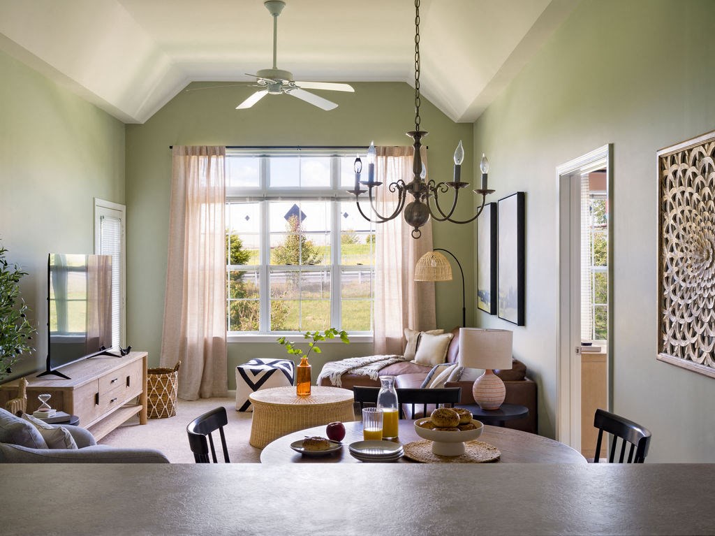 a living room with a table and a ceiling fan