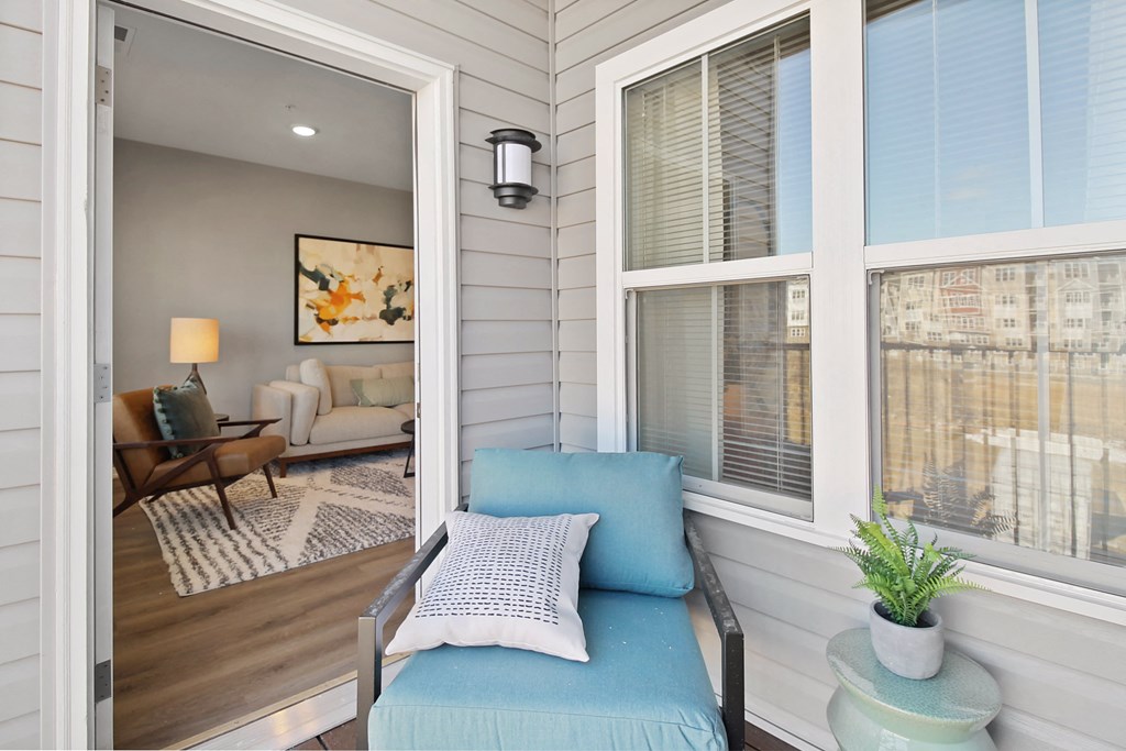 a small living room with a blue couch and large windows
