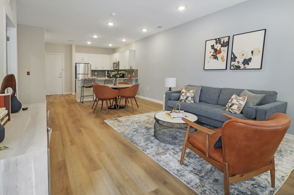 a living room with a couch and a table in front of a kitchen