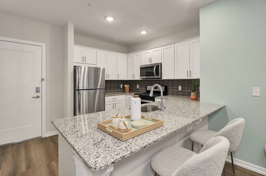 a kitchen with white cabinets and a granite counter top