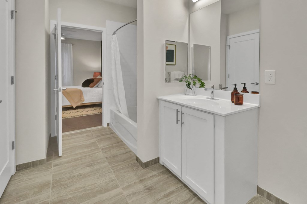 a bathroom with a sink and a mirror and a door to a bedroom