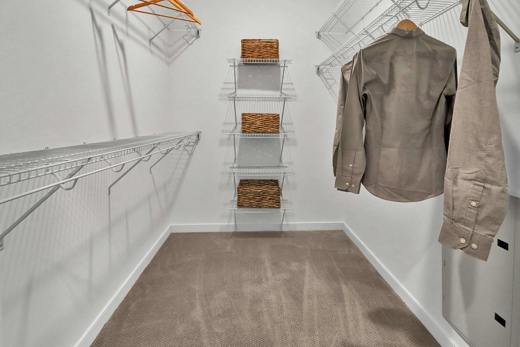 a walk in closet with two jackets hanging on metal racks