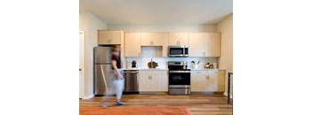 A kitchen with wooden cabinets and a person walking in front of it.