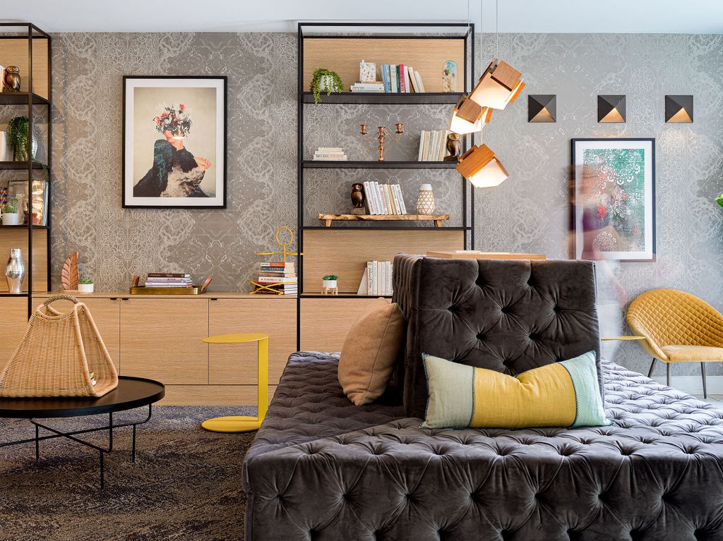 a living room with a black couch and yellow and gray pillows