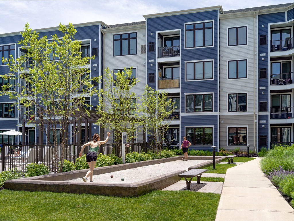 a woman playing on a sandbox in front of an apartment building