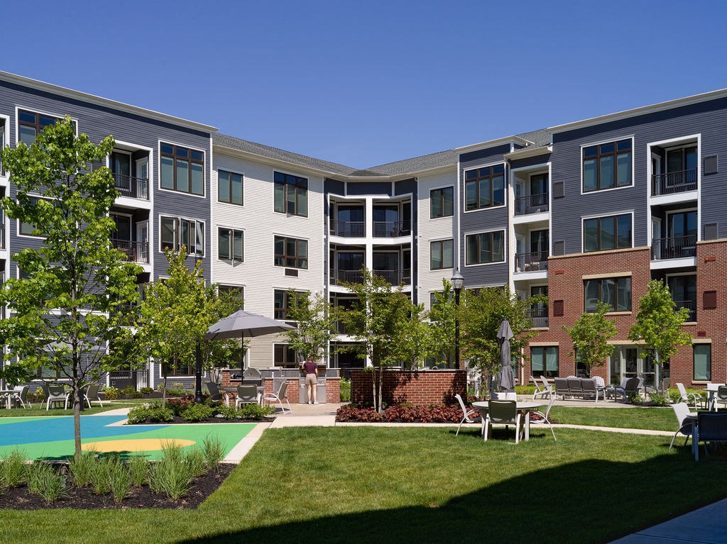an exterior view of an apartment complex with a courtyard and lawn
